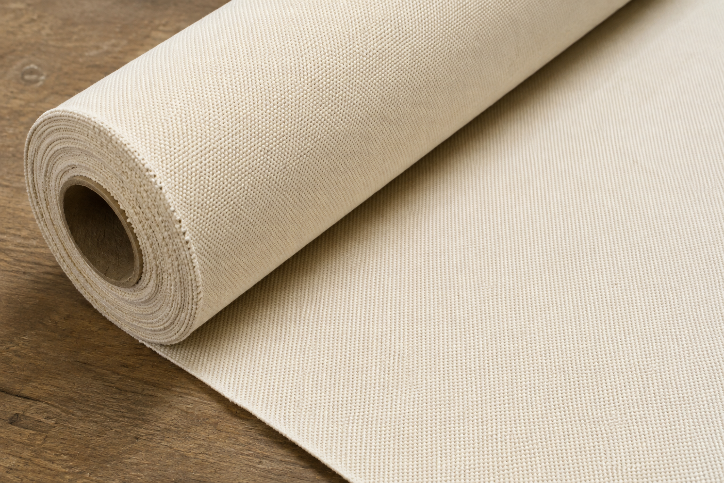 Extreme close-up of the tight, uniform weave texture on a rolled canvas